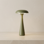Green table lamp on a beige surface with a neutral background