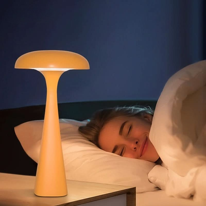 Person lying in bed with a yellow lamp on a nightstand