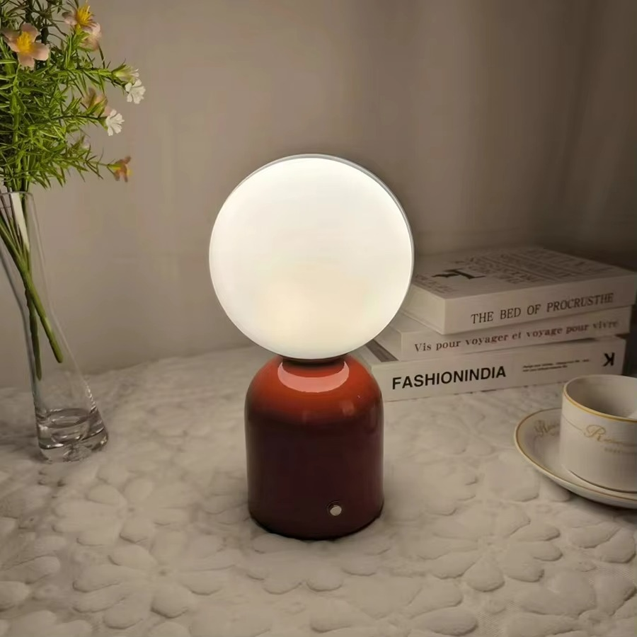 Table lamp with a white shade and brown base on a textured surface with books and a cup. 2