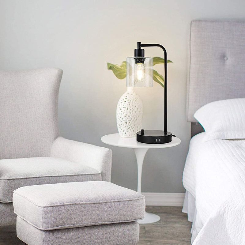 Modern bedroom with gray armchair, ottoman, and nightstand with decorative lamp.
