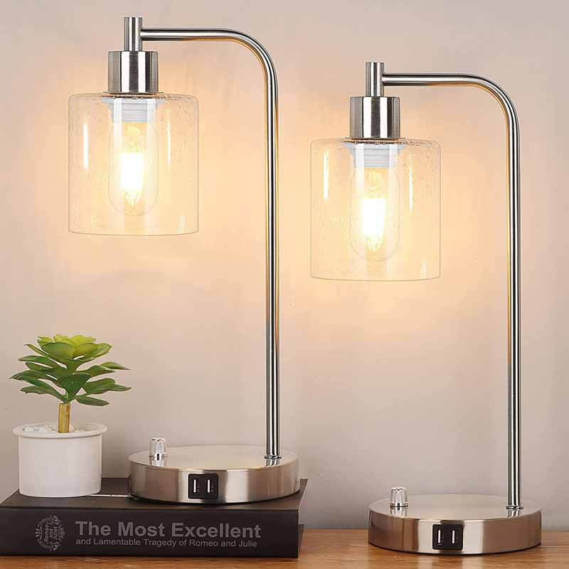 Two modern table lamps with glass shades on a wooden surface.