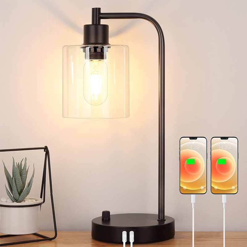 Modern table lamp with glass shade and USB ports on a wooden surface, with two smartphones displaying charging icons.