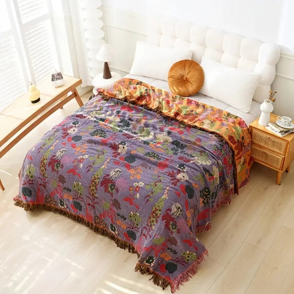 Colorful floral-patterned blanket on a bed in a bright bedroom.
