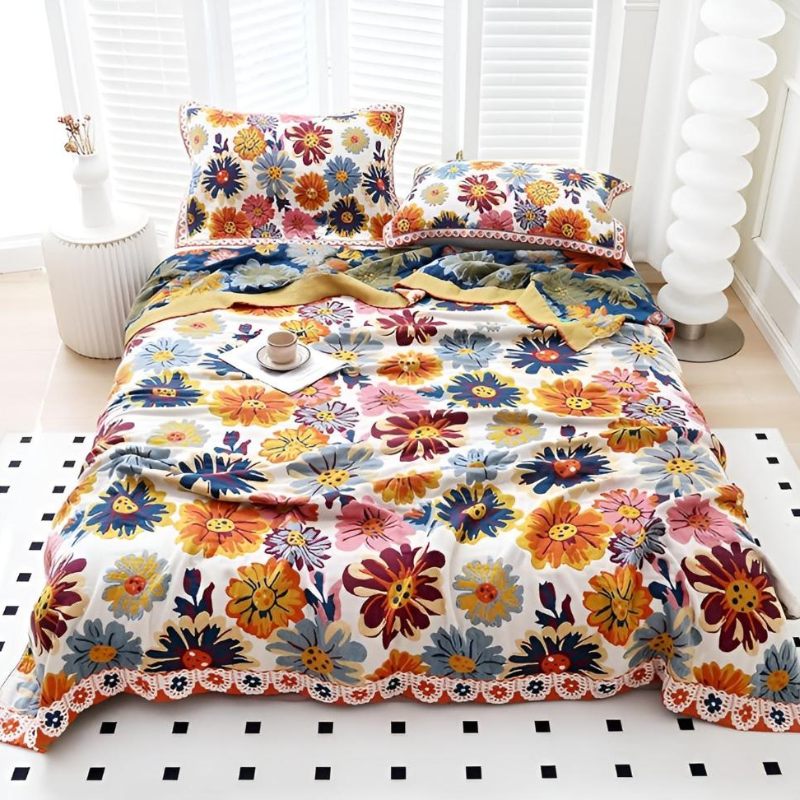 A bed dressed in a colorful floral print bedding set with matching pillowcases, styled in a bright bedroom setting with white shutters, a white side table, and a white floor rug.