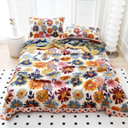 A bed dressed in a colorful floral print bedding set with matching pillowcases, styled in a bright bedroom setting with white shutters, a white side table, and a white floor rug.