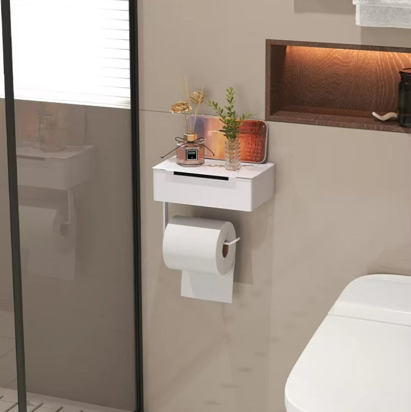 A white wall-mounted toilet paper holder shelf with a toilet paper roll attached, installed in a modern bathroom next to a toilet and shower glass.