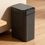 Black trash bin on a wooden floor with a neutral wall background