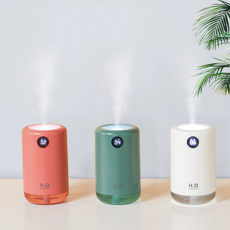 Three colorful humidifiers on a light surface with a plant in the background