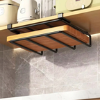 A wall-mounted kitchen shelf organizer with a black metal frame and wooden slats, holding a bamboo cutting board and other kitchen items on a wooden shelf above a gray marble-tiled wall.