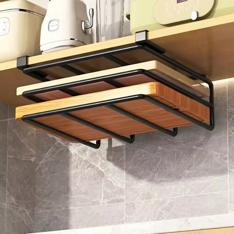 A wall-mounted black metal cutting board rack holding three wooden cutting boards, installed under a kitchen shelf with countertop items visible above.