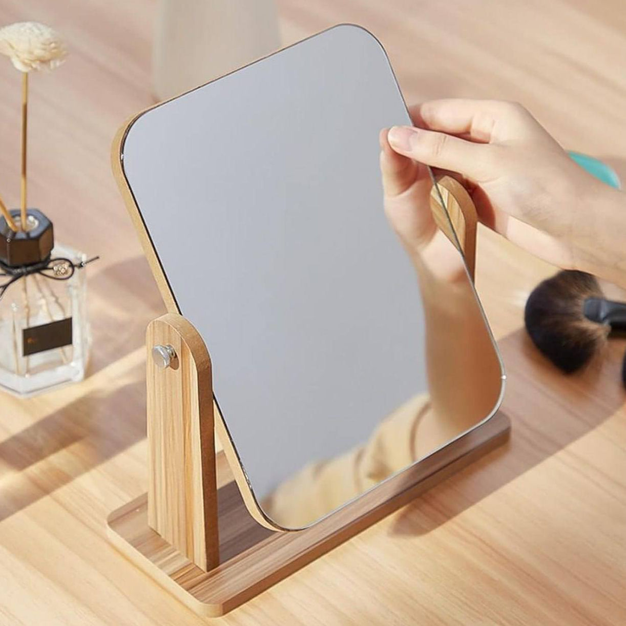 Handheld mirror with wooden stand on a wooden surface