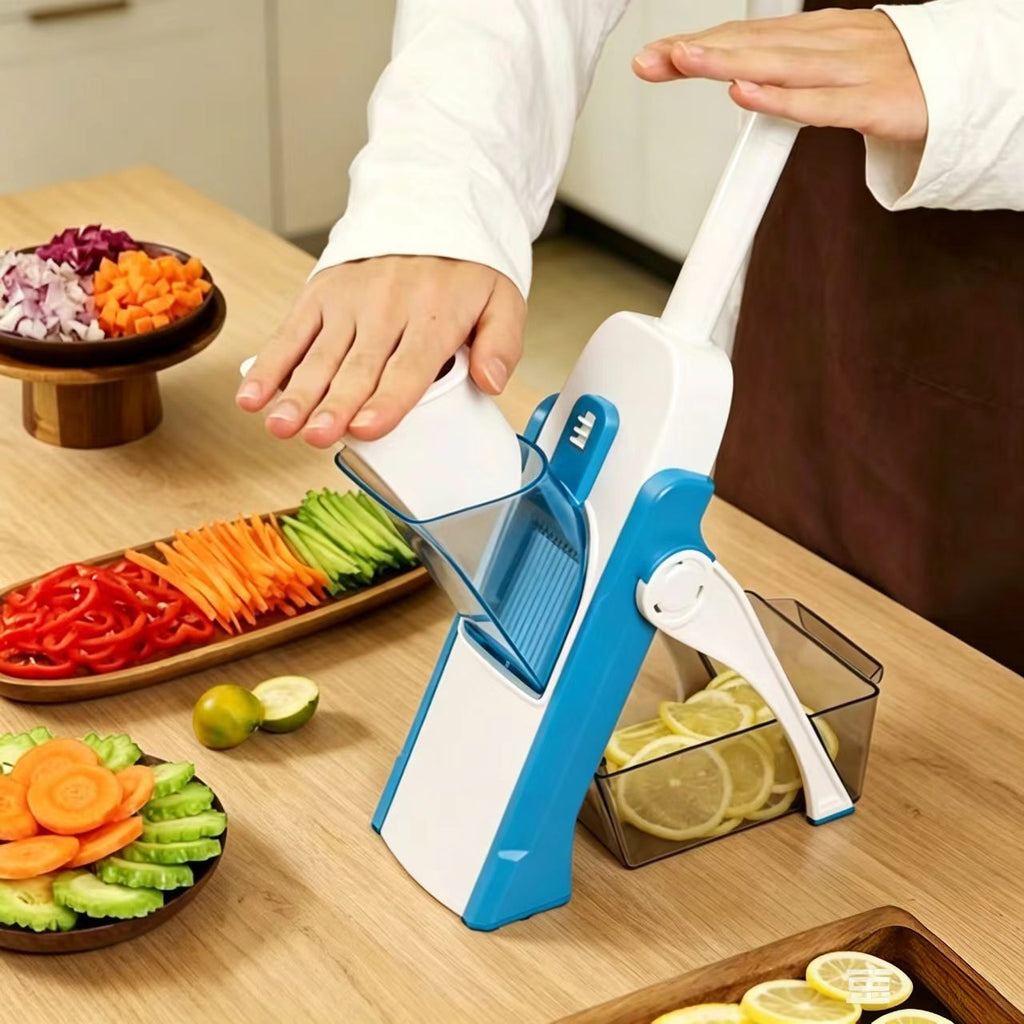 A person using a blue and white manual mandoline slicer on a wooden countertop, with sliced vegetables and lemon slices visible in containers and around the workspace.