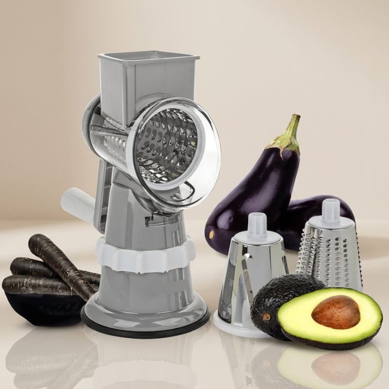 A kitchen multi-tool set featuring a meat grinder and two detachable graters, shown with various vegetables including eggplants, carrots, avocado, and a halved avocado on a reflective beige surface.