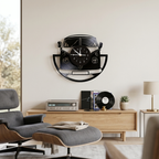 A black wall clock shaped like a classic Volkswagen camper van, mounted on a light beige wall in a modern living room setting.