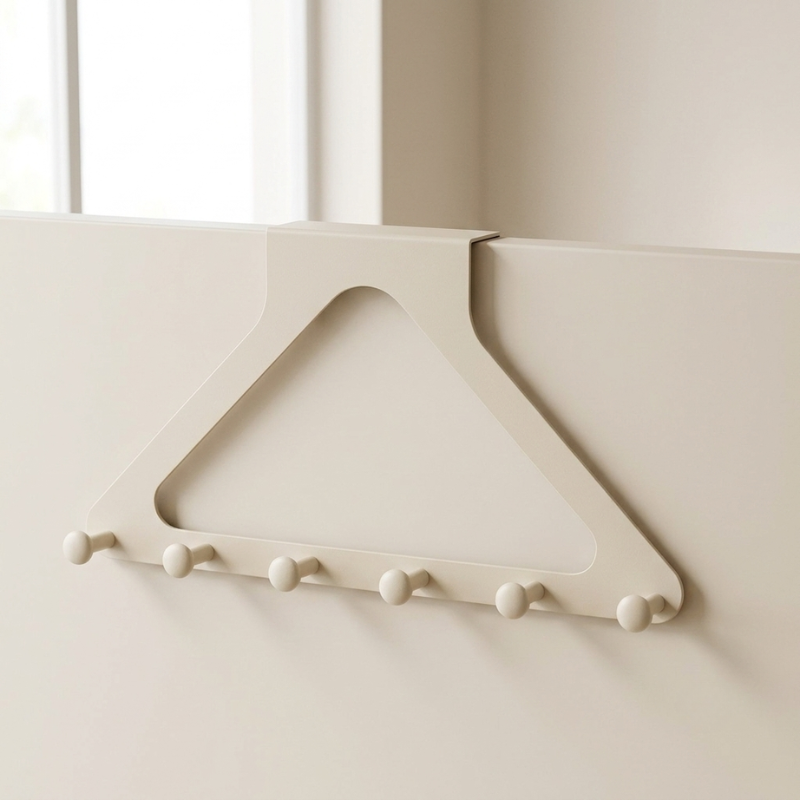 A cream-colored triangular wall hook holder with five round peg hooks, shown attached to a matching cream-colored door or panel in a minimalist interior setting.