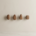 Four wooden wall hooks of different shapes on a beige background
