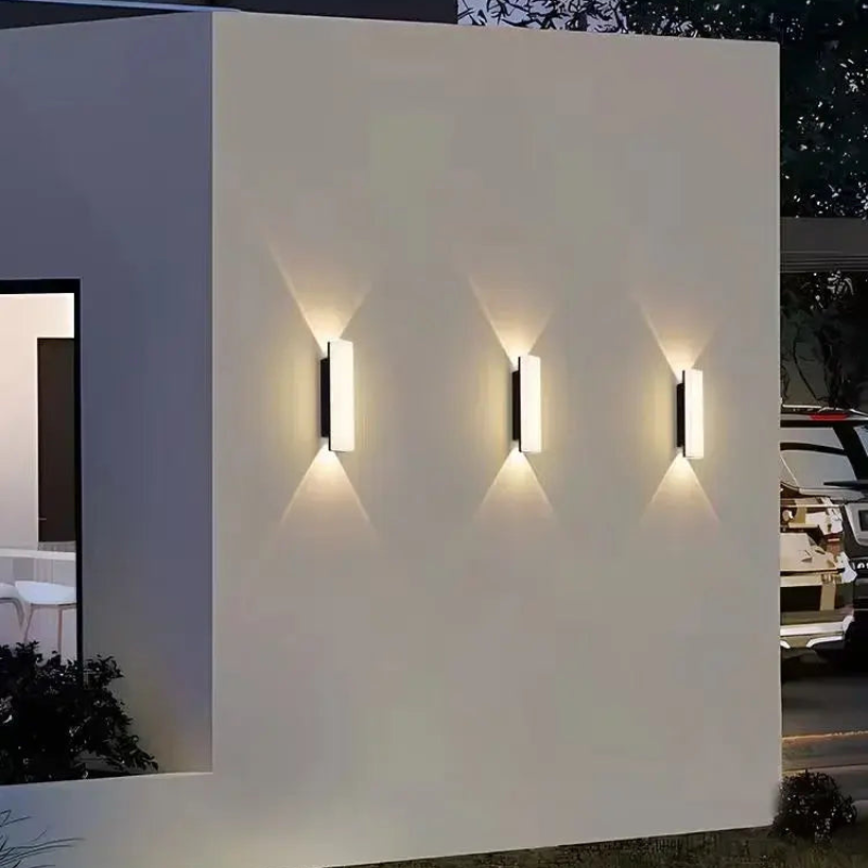 Modern outdoor wall lights on a white wall with a night-time background.