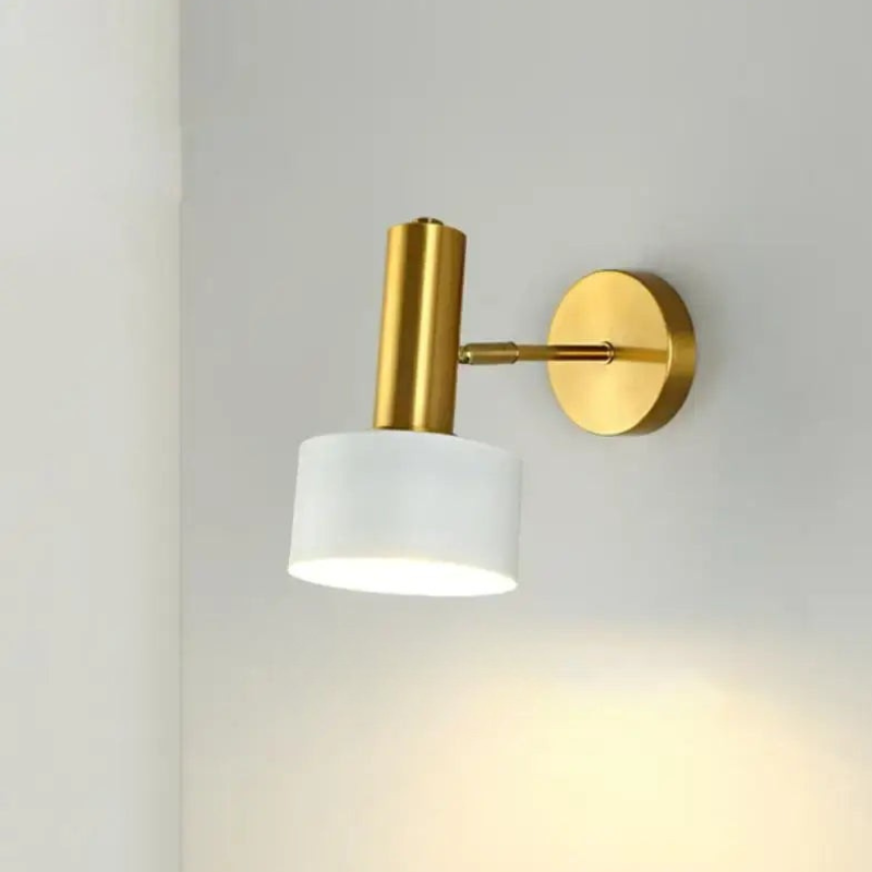Wall-mounted light fixture with gold finish and white shade on a plain wall.