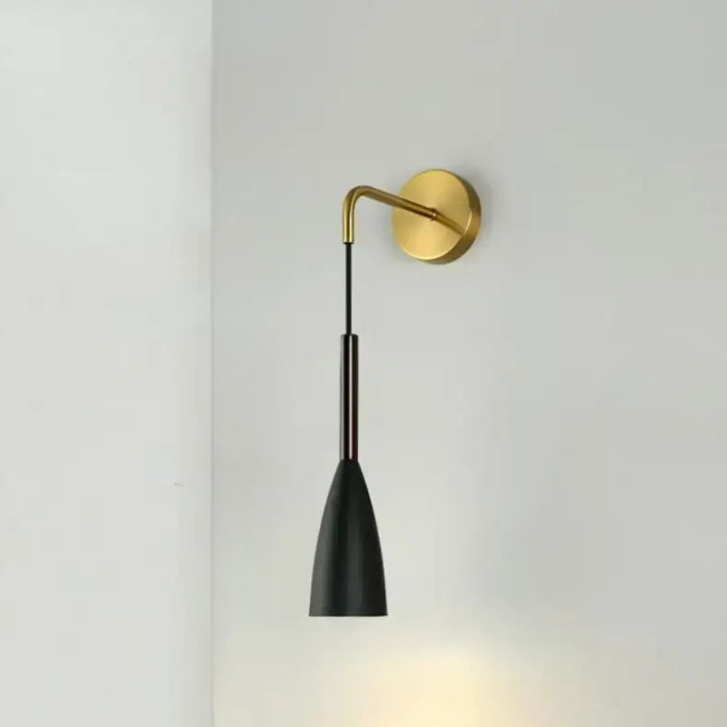 Wall-mounted lamp with black shade and gold arm on a light gray background