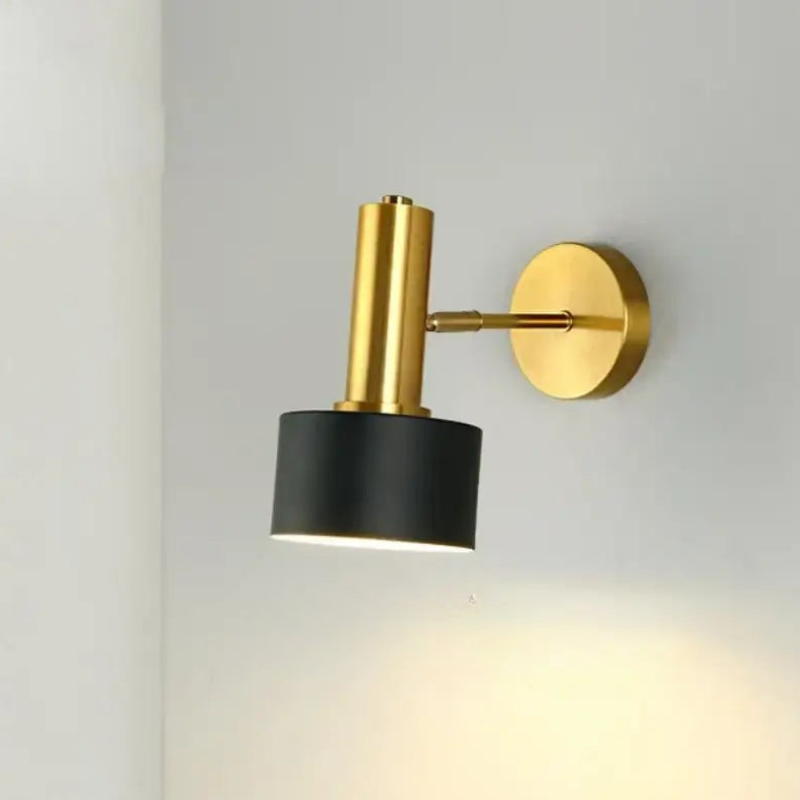 Wall-mounted light fixture with gold and black design on a white wall.