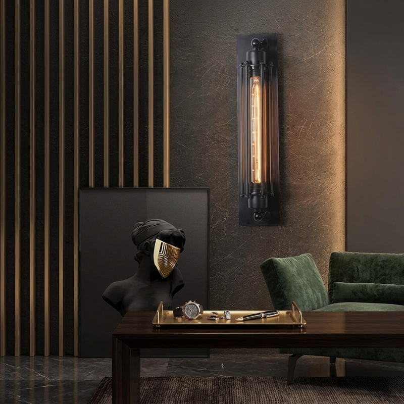 Modern interior with wall sconce, green sofa, and decorative items on a table.