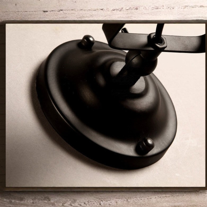Black metal wall-mounted lamp on a textured beige background