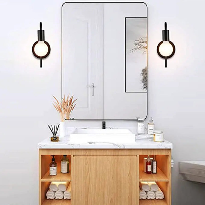 Bathroom vanity with mirror, lights, and various items on a white wall.