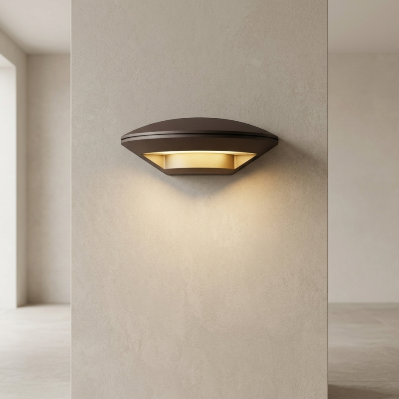 A modern wall-mounted outdoor light fixture with a dark bronze finish and warm yellow LED lighting, shown mounted on a textured beige wall in a minimalist architectural setting.