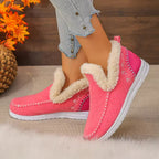 Pink winter slip-on shoes with fluffy cream faux-fur trim, shown on a model wearing light blue jeans. The shoes feature white soles and decorative stitching.
