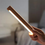 Hand holding a cylindrical light source with a blurred indoor background