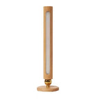 Tall cylindrical lamp with wooden base and gold accent on a white background