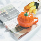 Orange pumpkin-shaped mug on a newspaper with squash in the background
