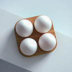 Four white eggs on a wooden tray with a light gray background
