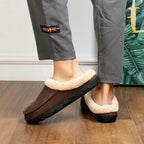 Brown slippers with beige fur lining worn indoors on a wooden floor.