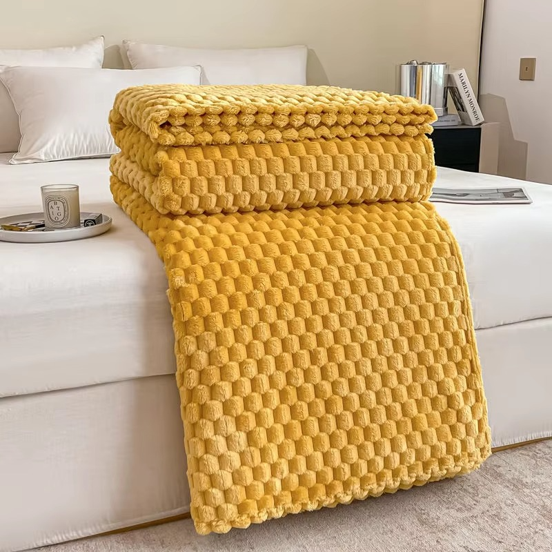 Yellow textured blanket draped over a white sofa in a living room setting.