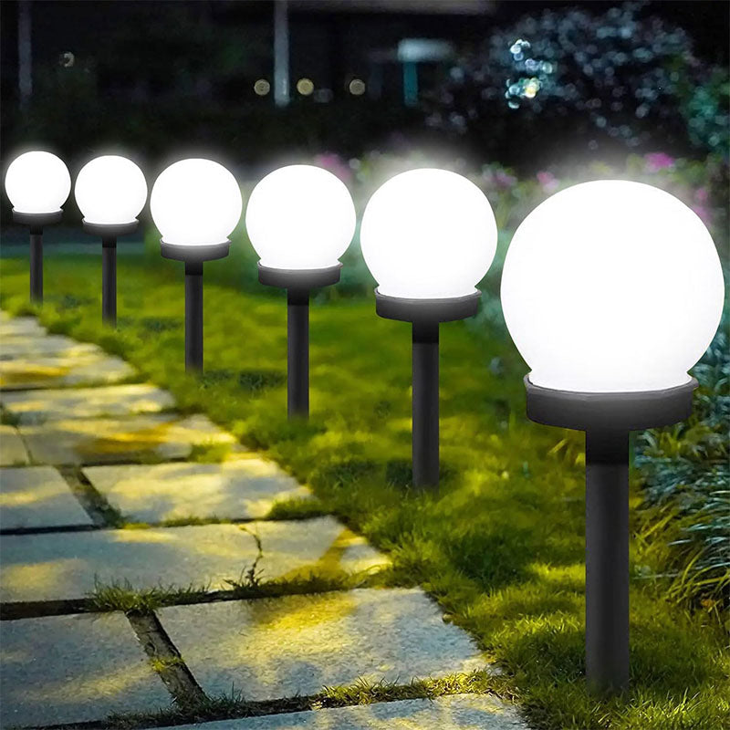Glowing spherical garden lights on stakes along a stone pathway.