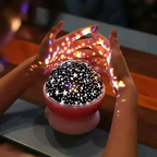 Starry night light projector with hands holding it, creating star patterns on a blurred background