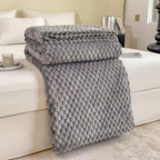 Gray textured blanket draped over a white sofa in a living room setting.