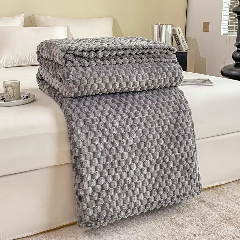 Gray textured blanket draped over a white sofa in a living room setting.