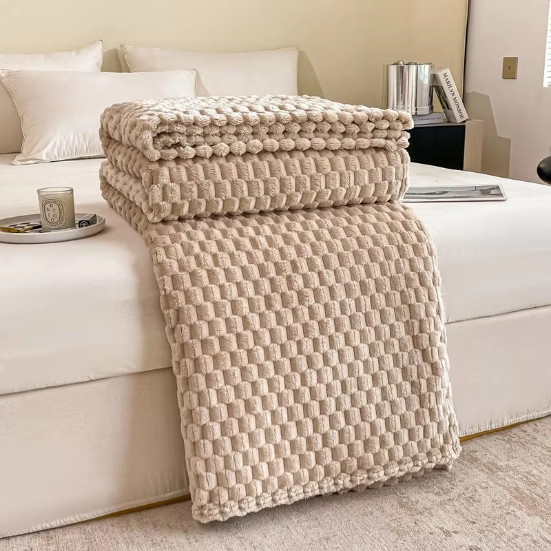 Beige textured blanket draped over a white sofa in a living room setting.