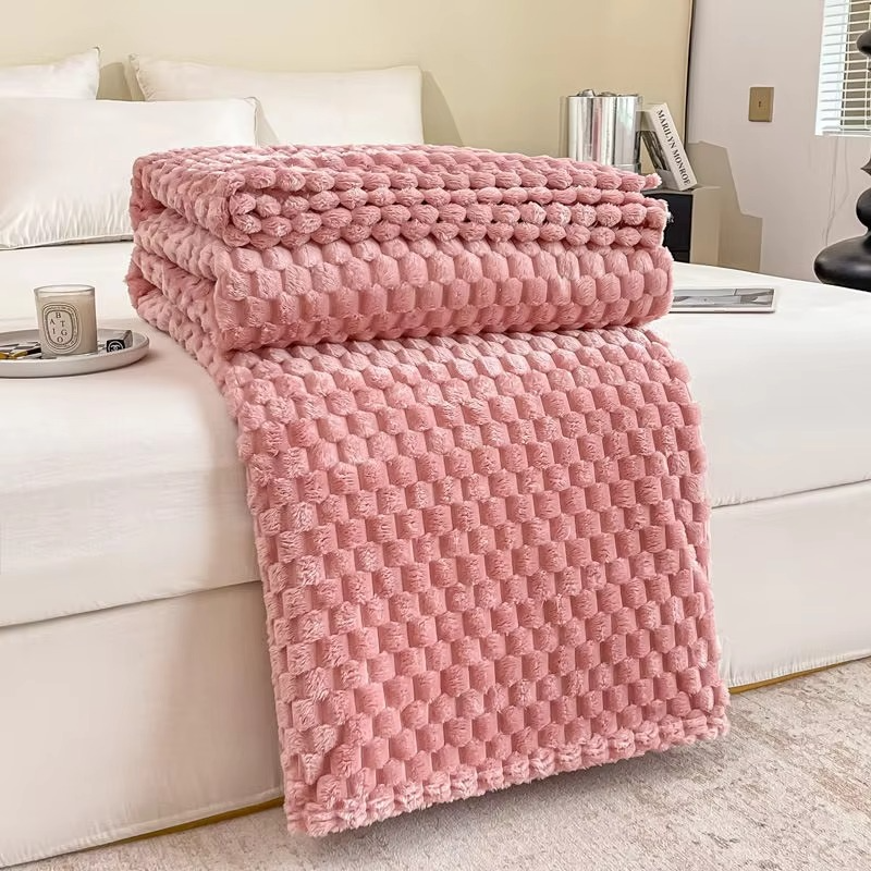 Pink textured blanket draped over a white sofa in a living room setting.