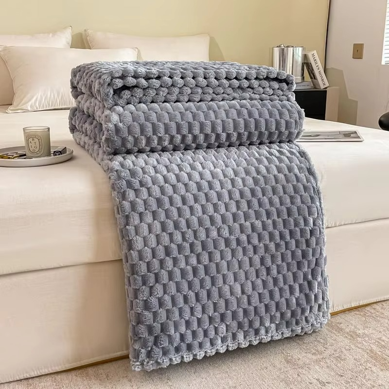 Gray textured blanket draped over a white sofa in a living room setting.