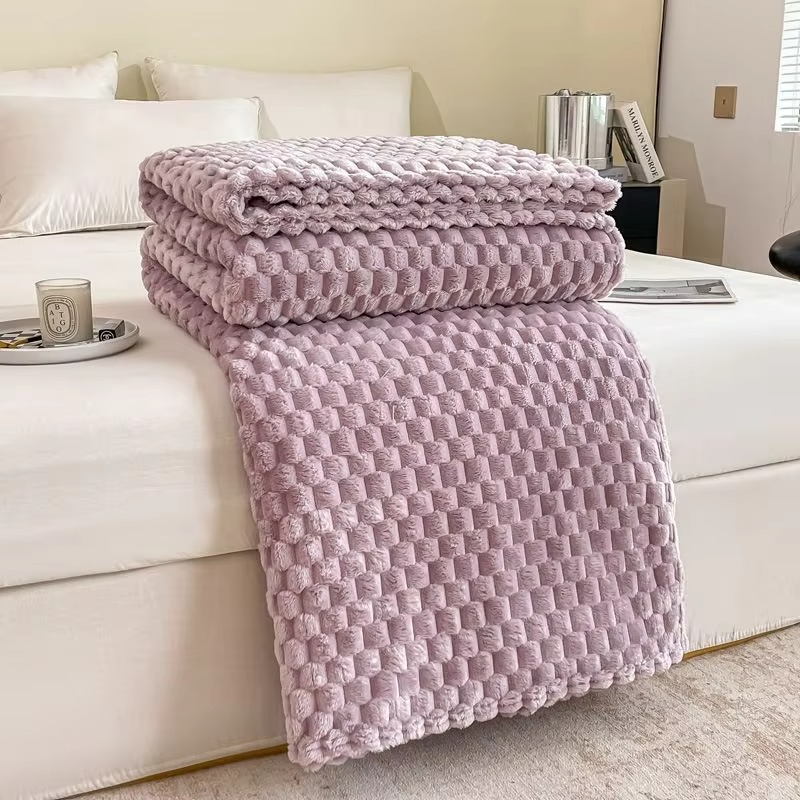 Pink textured blanket draped over a white sofa in a living room setting.