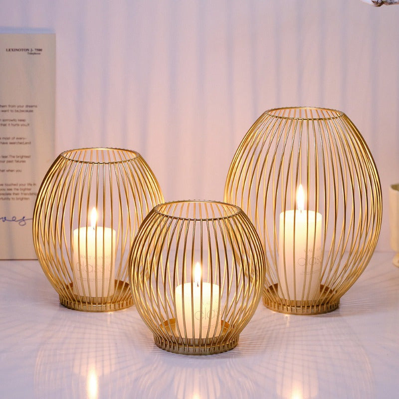 Three gold wire candle holders with candles on a textured surface.