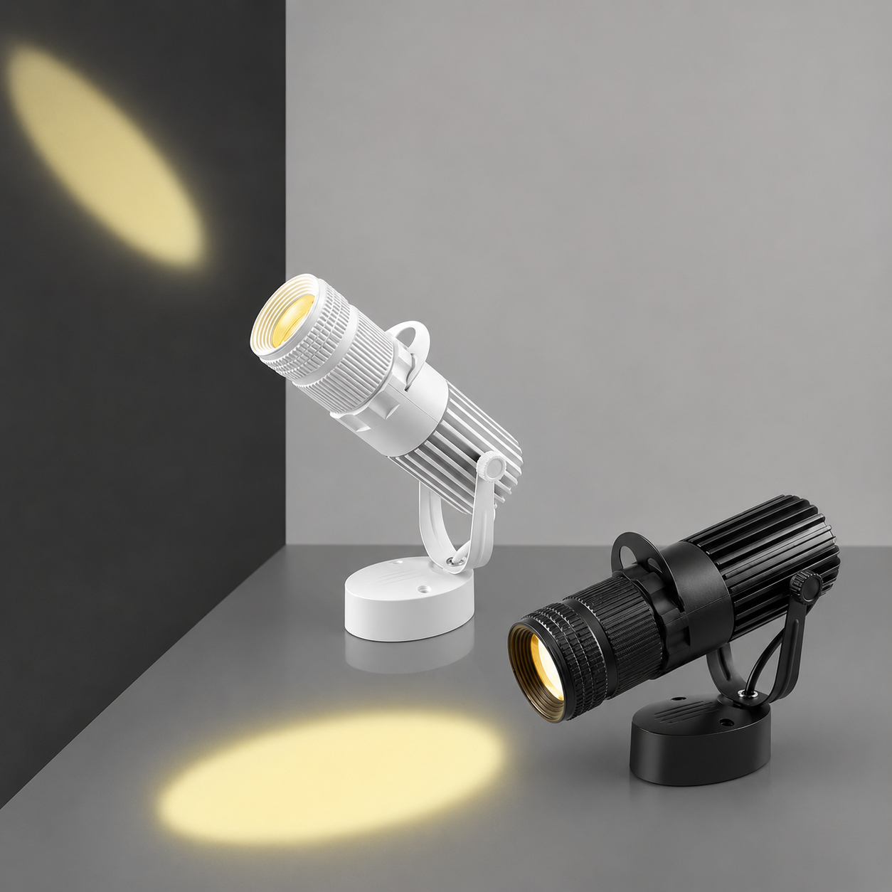 Two spotlight lamps, one white and one black, on a gray surface with a dark background.