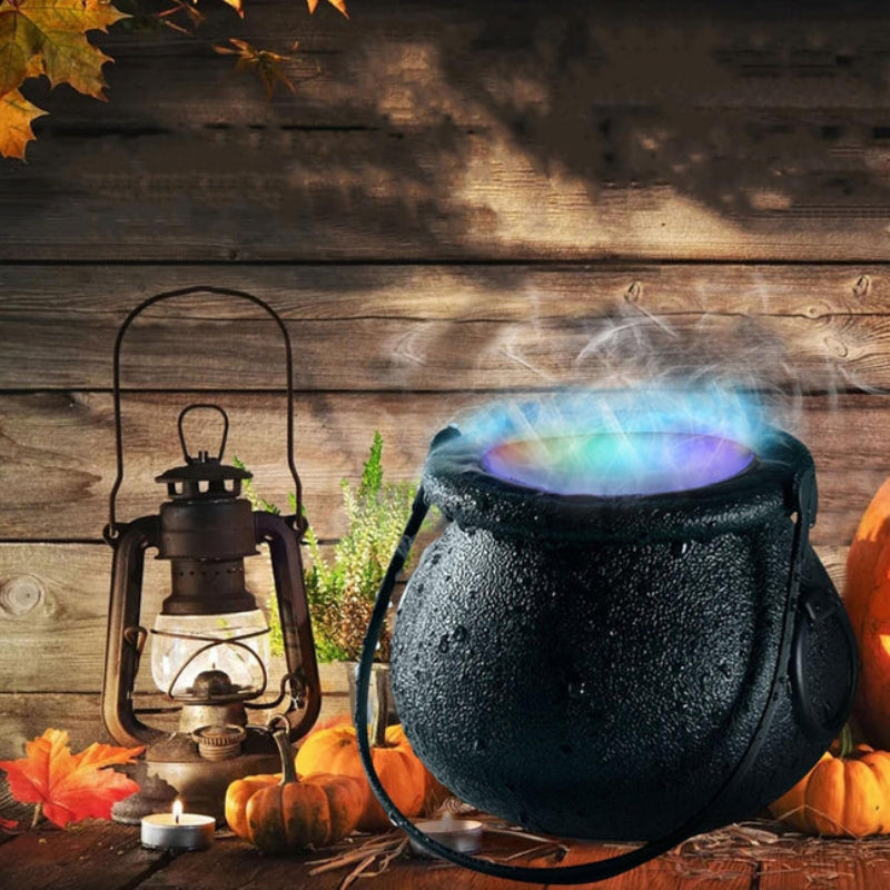 Black cauldron with colorful smoke, lantern, pumpkins, and autumn leaves on a wooden background