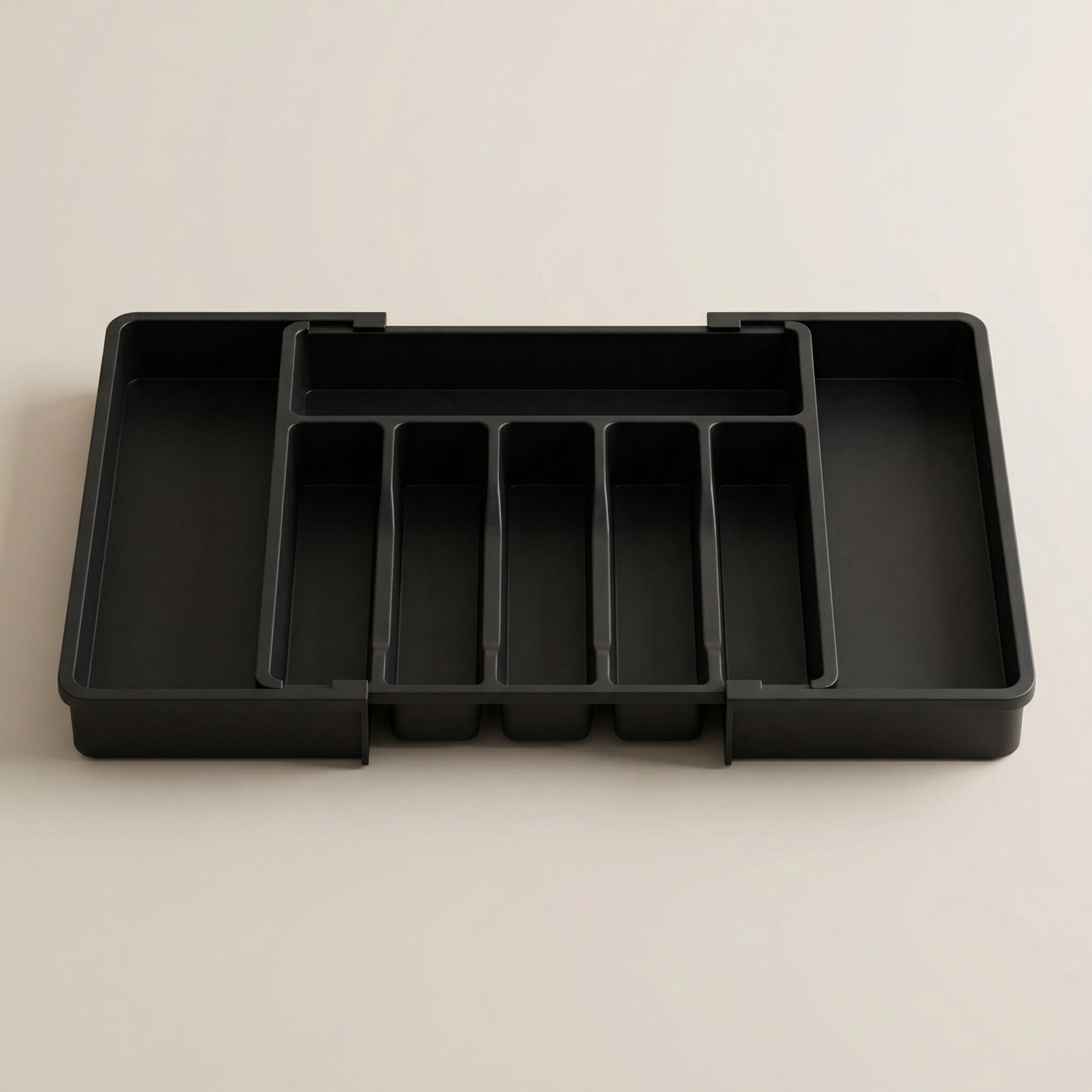 Black plastic tray with compartments on a beige background