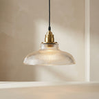 Pendant light with glass shade and brass fitting on a neutral background