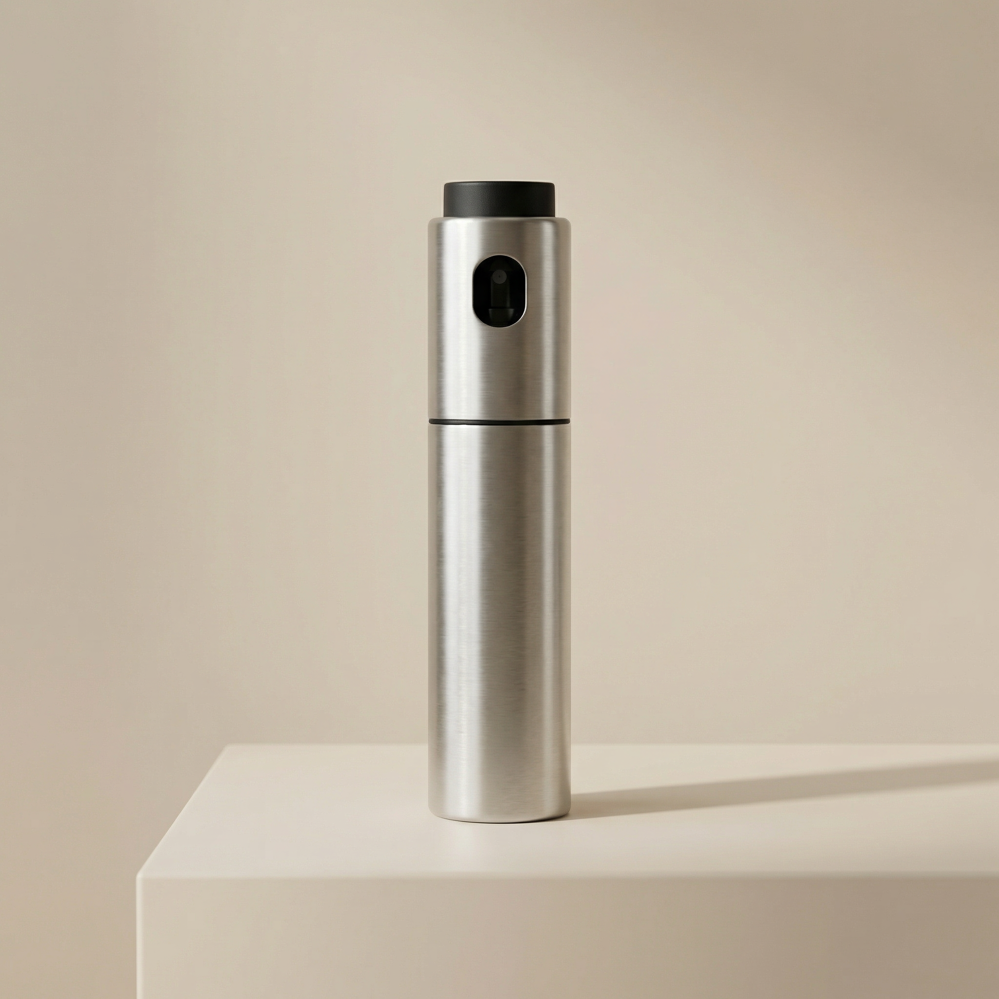Silver pepper grinder on a beige surface with a beige background