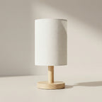 Table lamp with wooden base and white fabric shade on a neutral background